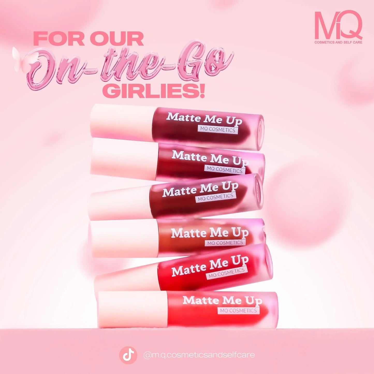 Five Matte Me Up liquid lipsticks in pink, red, and mauve shades on a soft pink background.