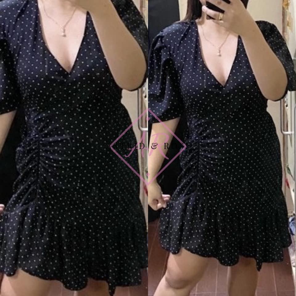 Plus size black polka dot dress with v-neck, ruched waist and ruffled hem shown on model