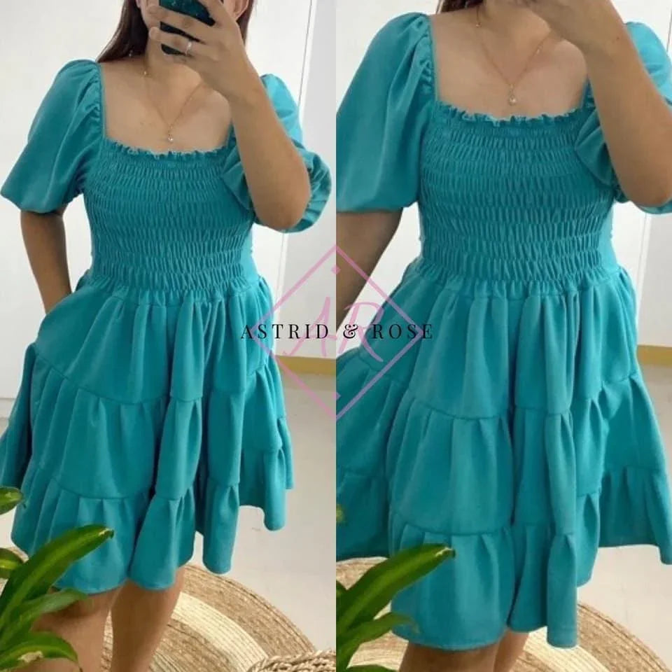 Woman modeling a blue plus size smocked dress with puff sleeves and tiered skirt