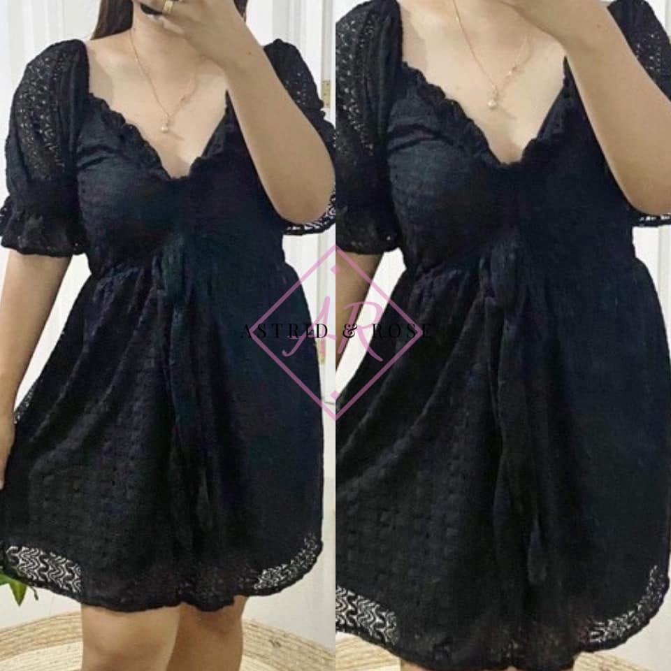 Woman wearing plus size black short dress with puff sleeves and lace trim details