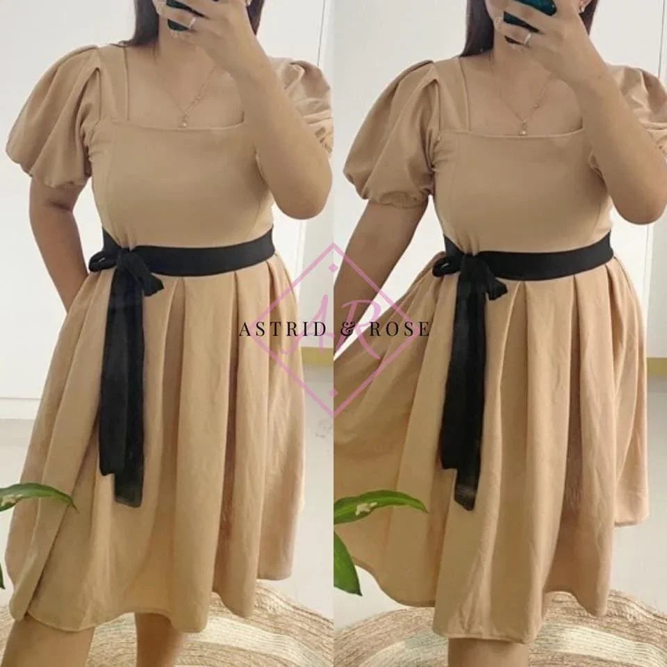 Plus size beige puff sleeve dress with black waist tie, shown on a model indoors