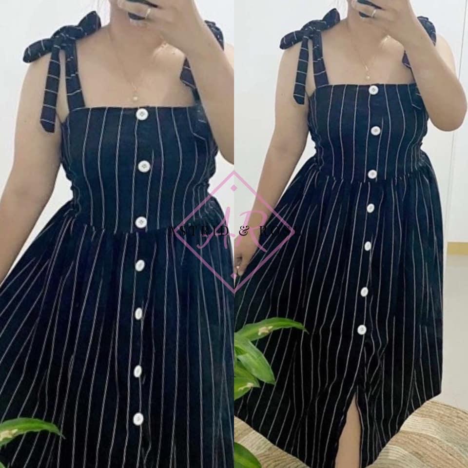Plus size black pinstripe dress with front buttons and tie shoulder straps, shown indoors