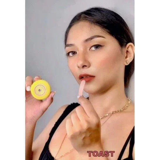 Woman applying tinted lip balm in toast shade, holding open lip balm container