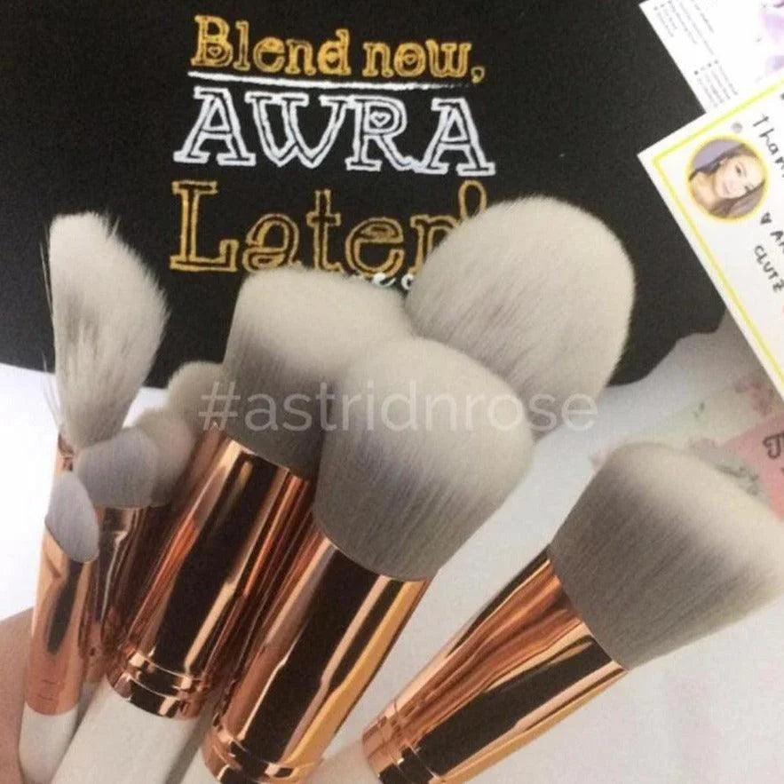 Set of soft makeup brushes with rose gold handles, ideal for beginners, on a styled background.